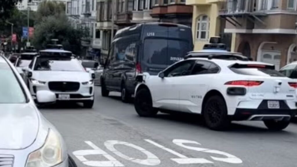Waymo Jaguar I-Pace robotaxis parked along a street.