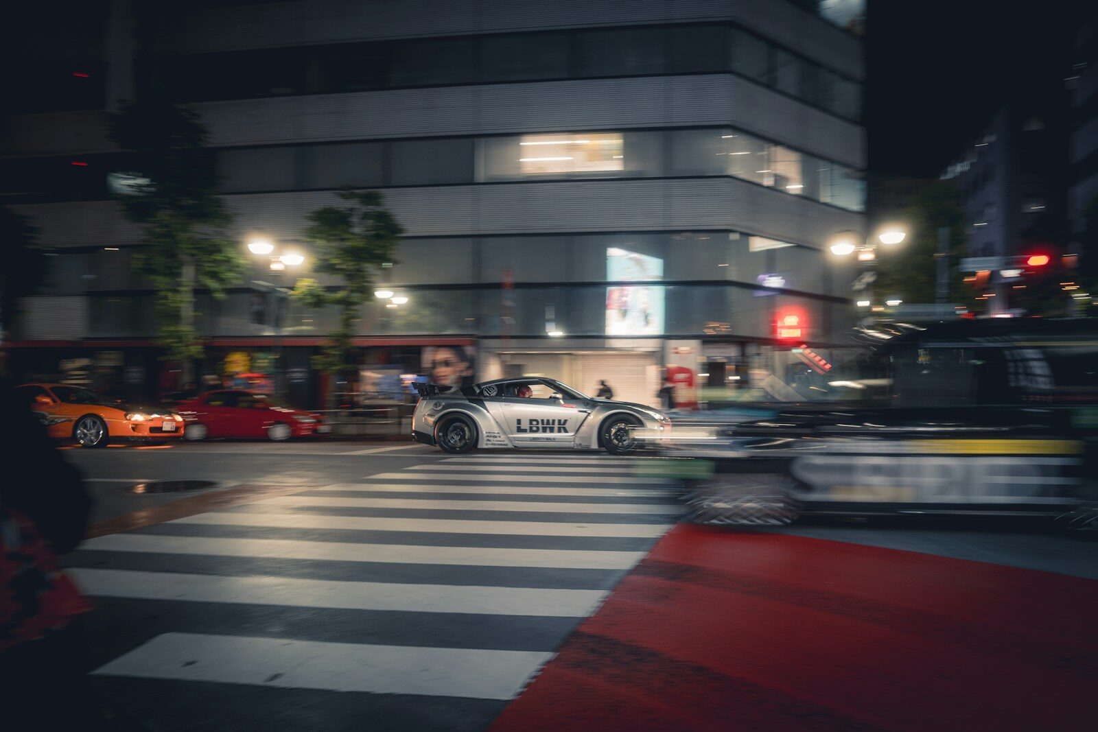 Cars crossing a street at night in a city