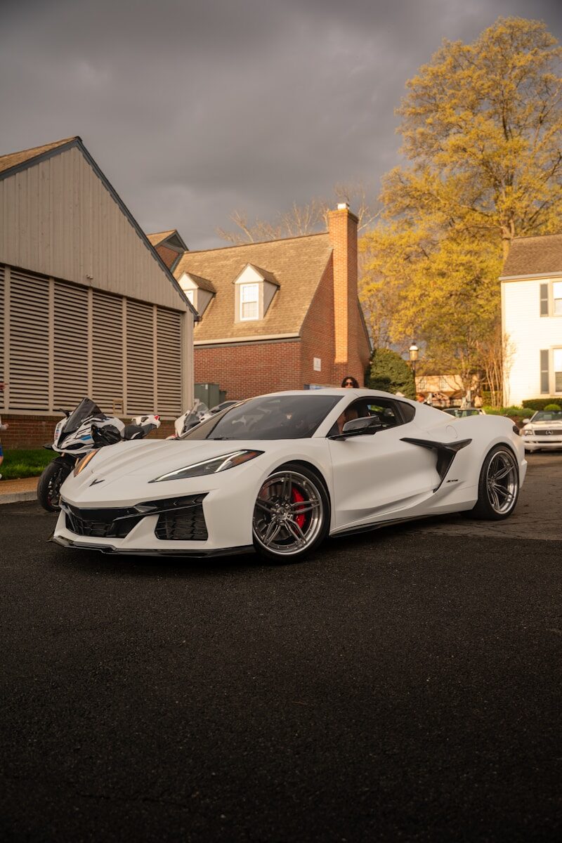 A white sports car parked outdoors with buildings behind it.
