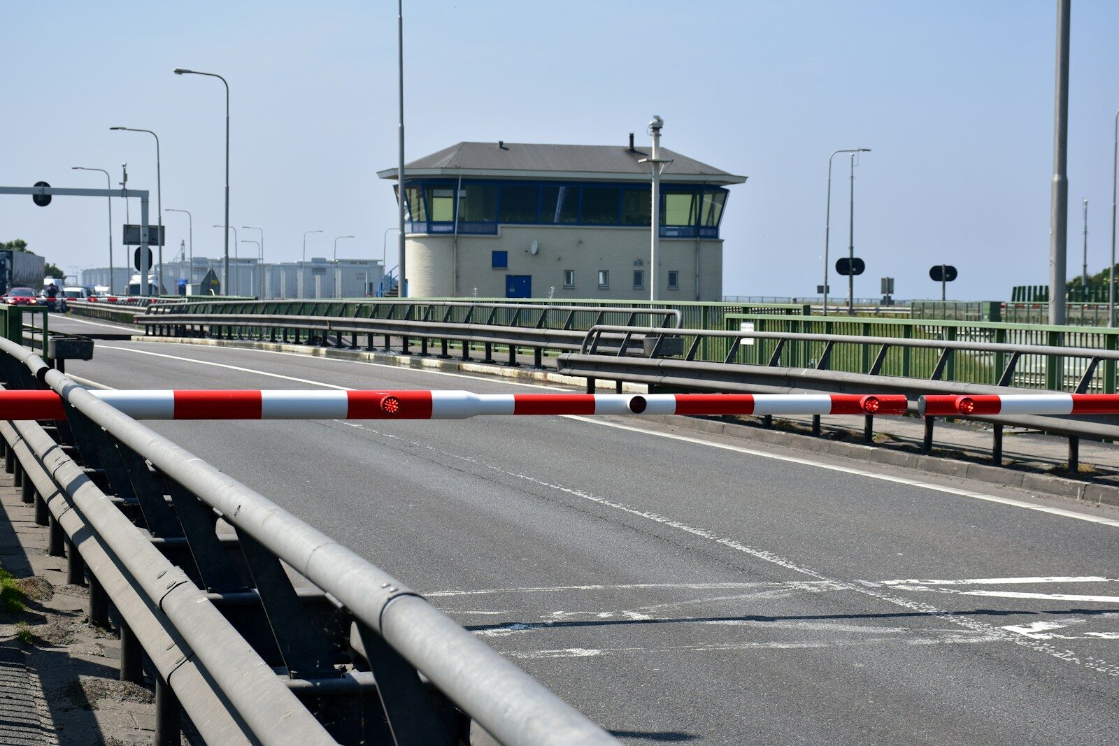 A road with a barrier and a control tower building.