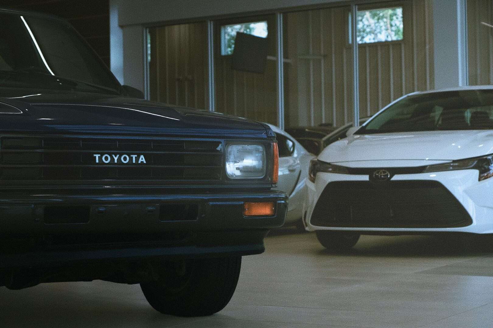 Classic and modern toyota cars parked indoors.