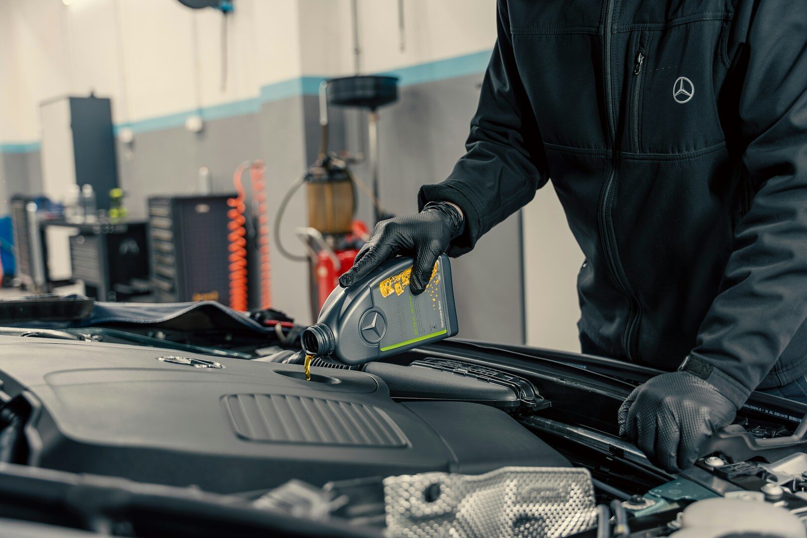 Mechanic at a quick-lube shop pouring oil into a car engine