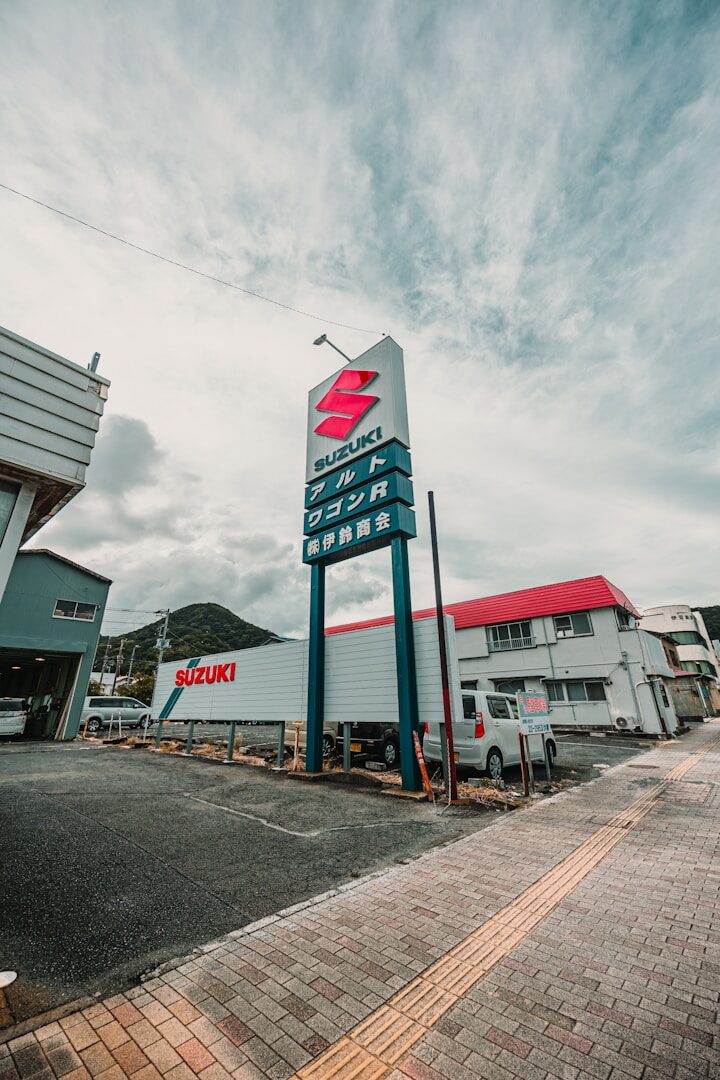 Suzuki dealership with a large sign and buildings.