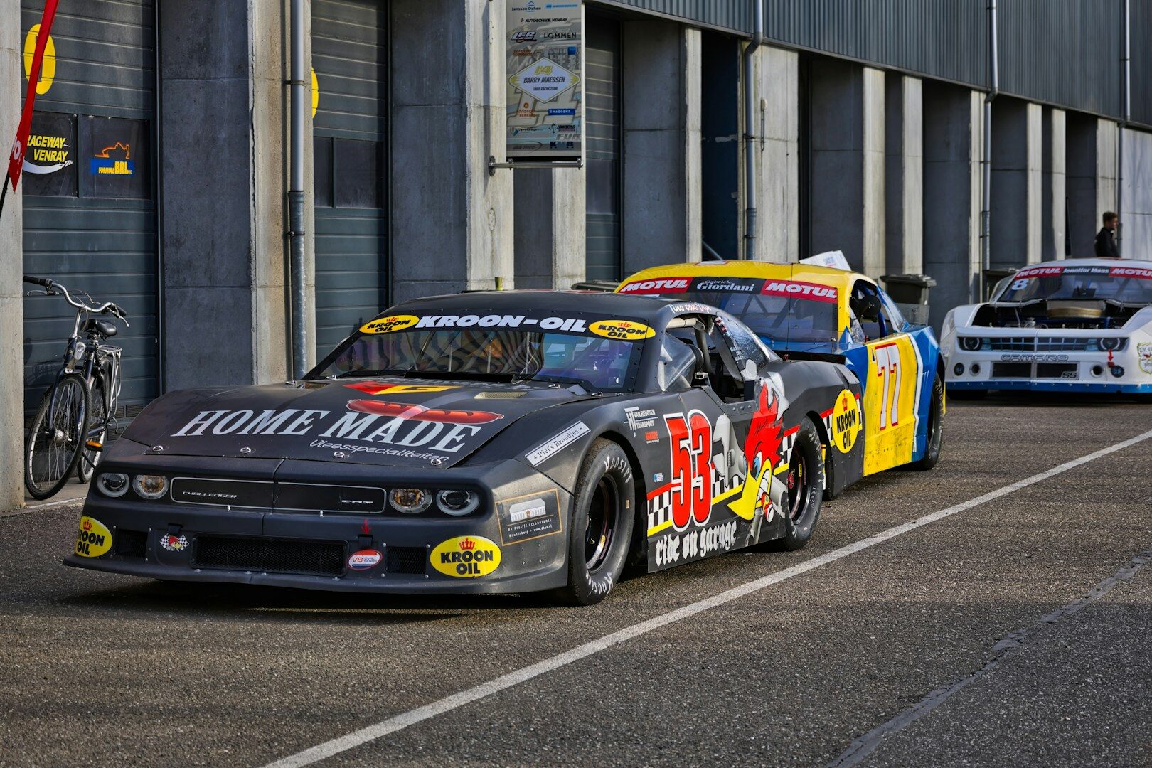 Short-track stock cars racing on an oval track, similar to the grassroots Legend car circuit that feeds NASCAR's development pipeline