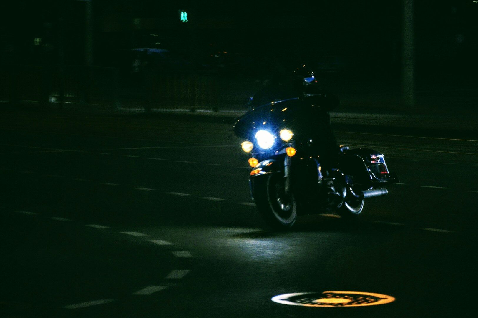 A motorcycle rides at night with bright headlights.