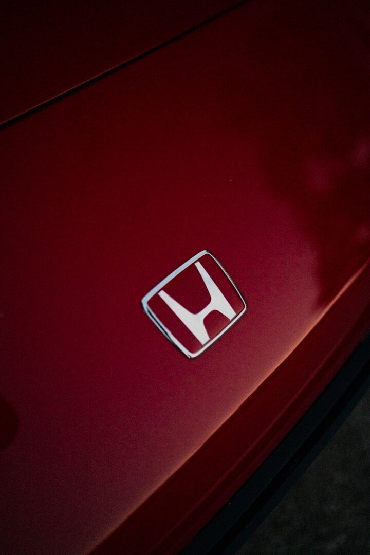 Close-up of a red car's honda emblem.