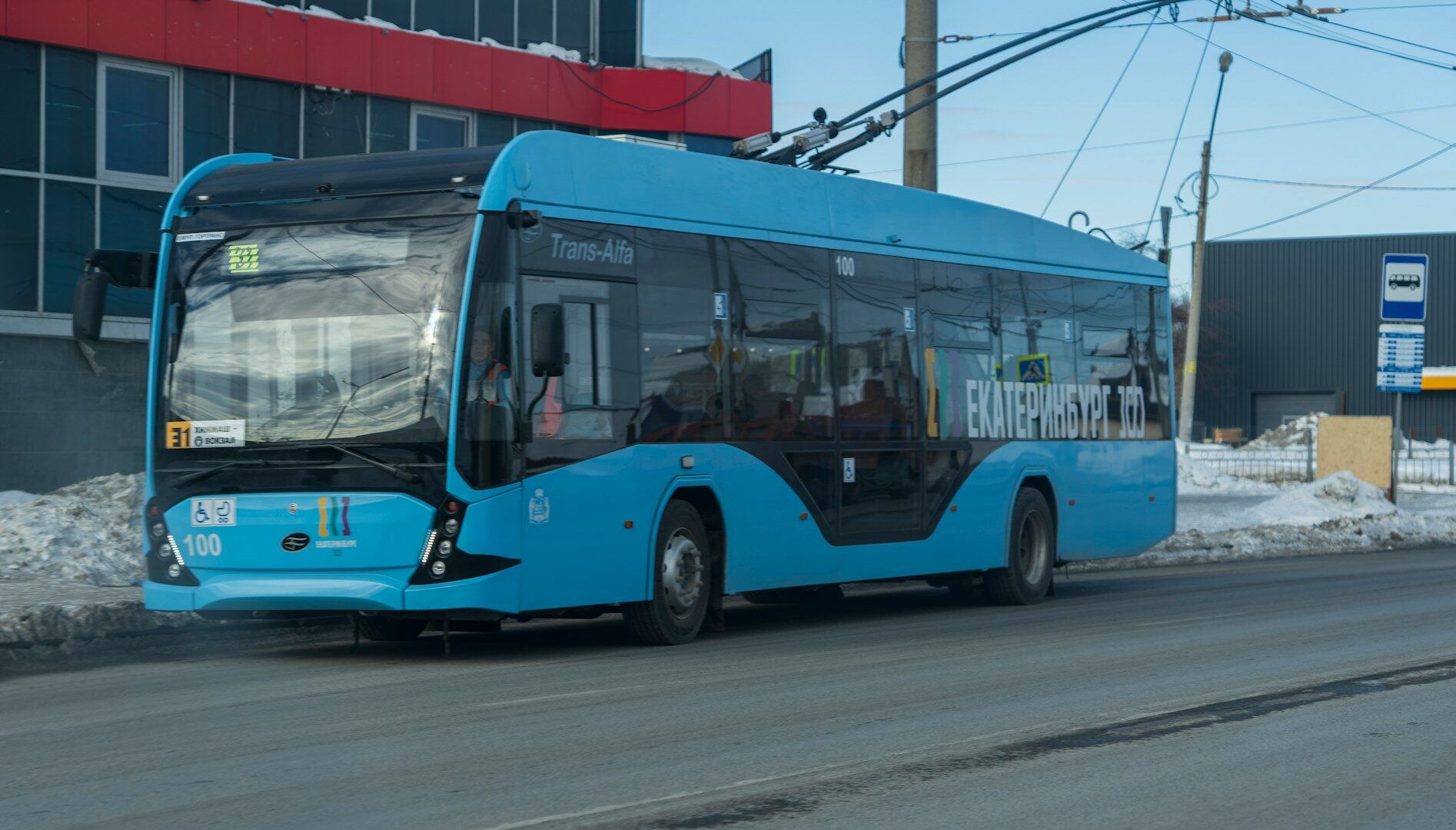 a blue bus driving down a street next to a tall building