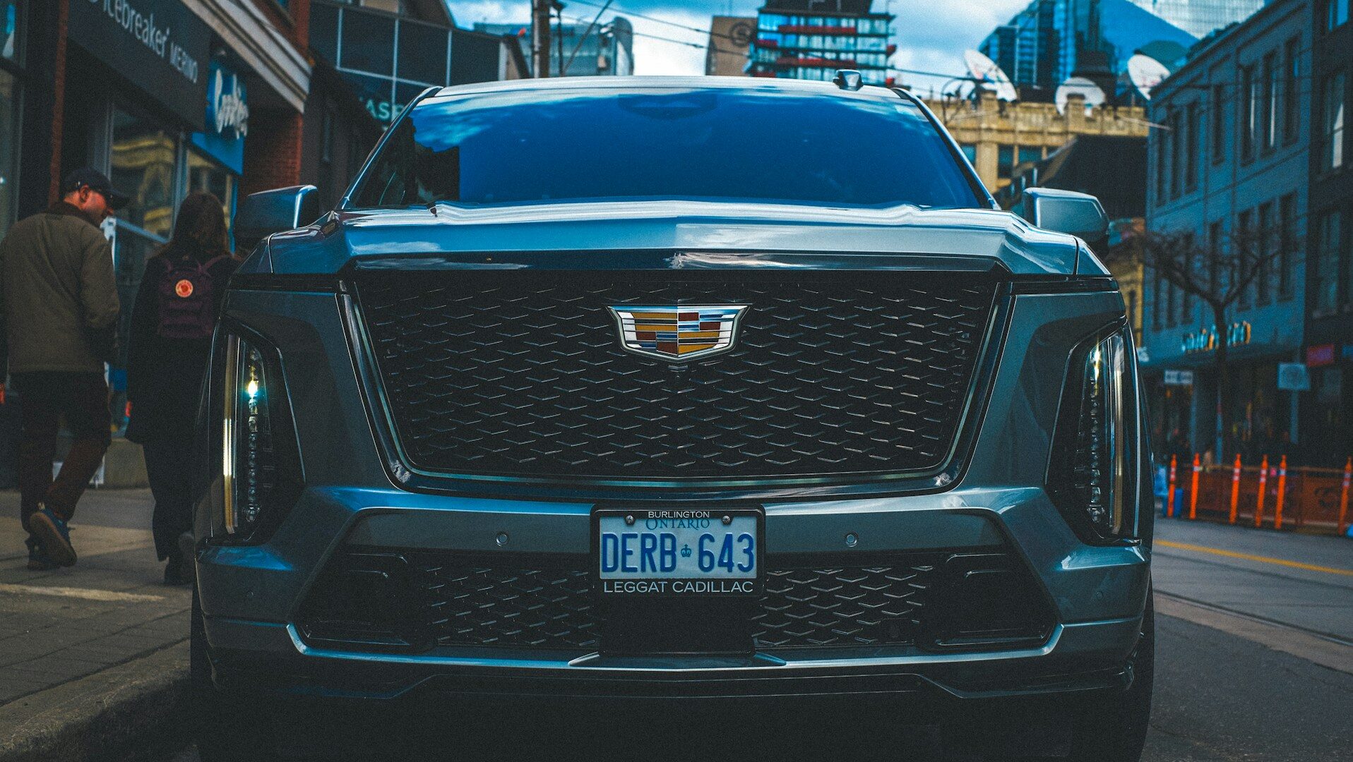 A dark grey cadillac suv parked on a city street