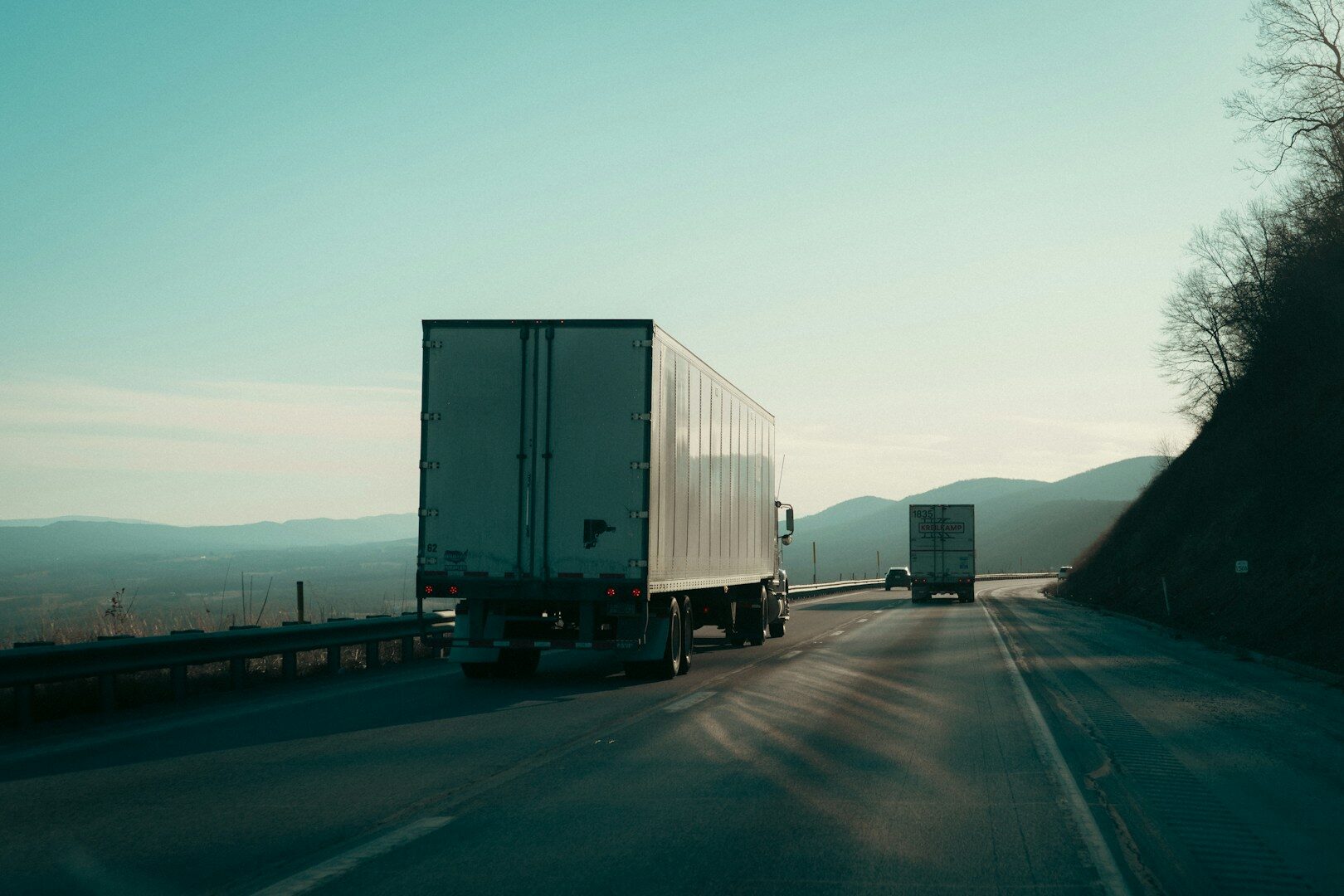 Two semi-trucks driving on a highway.