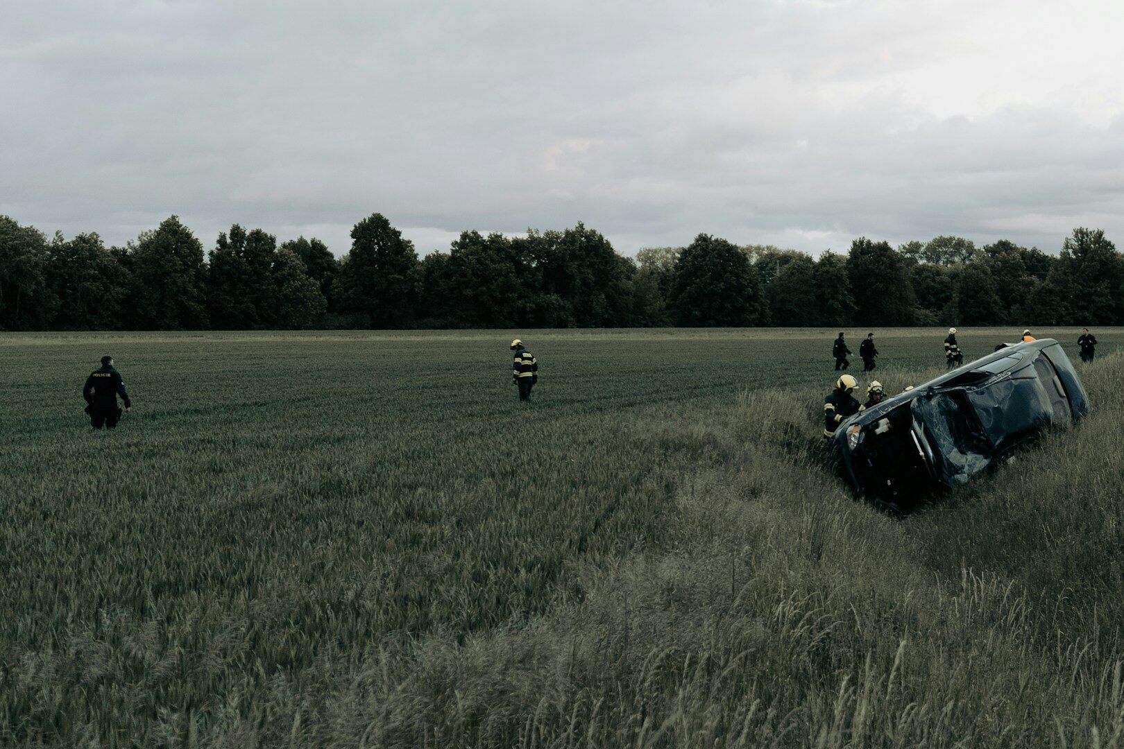 A car is flipped over in a grassy field.
