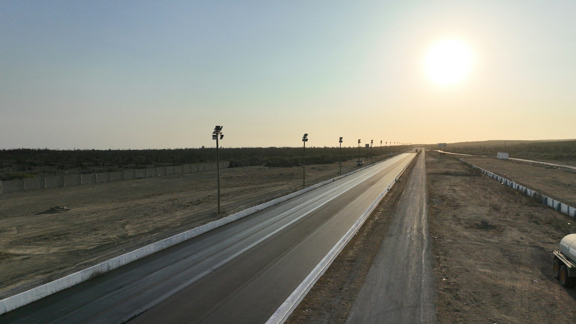 Desert highway at sunset with distant palm trees