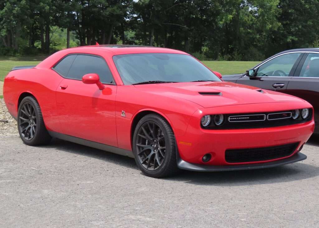 A red 2017 Dodge Challenger R/T Scat Pack parked on gravel, front three-quarter view