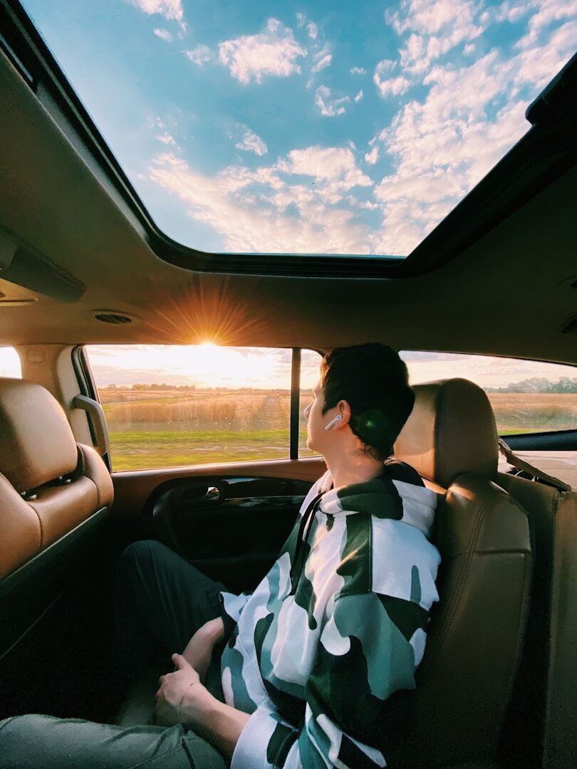 woman in white and black floral shirt driving car during daytime