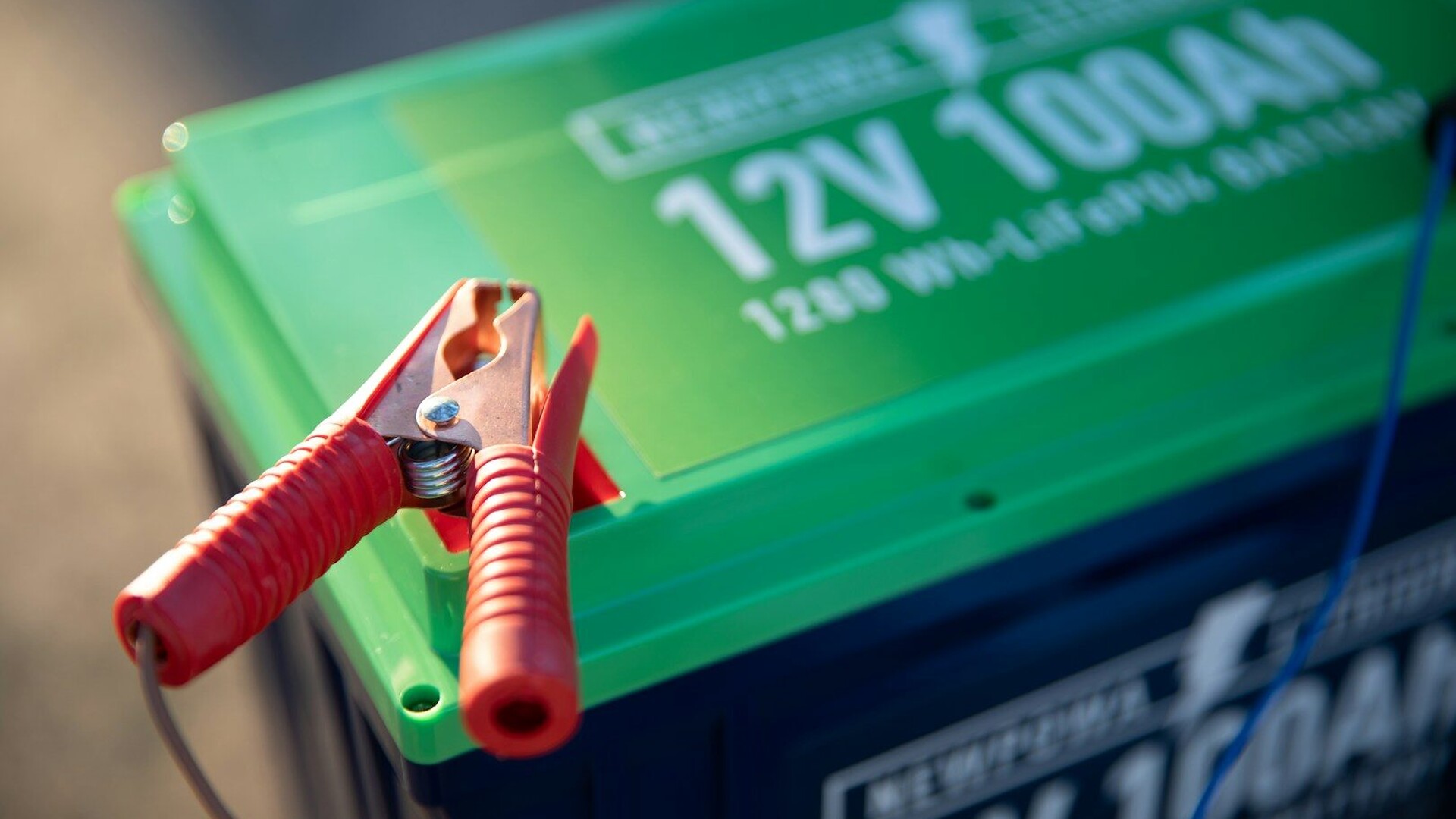 a red and green battery with a pair of pliers attached to it