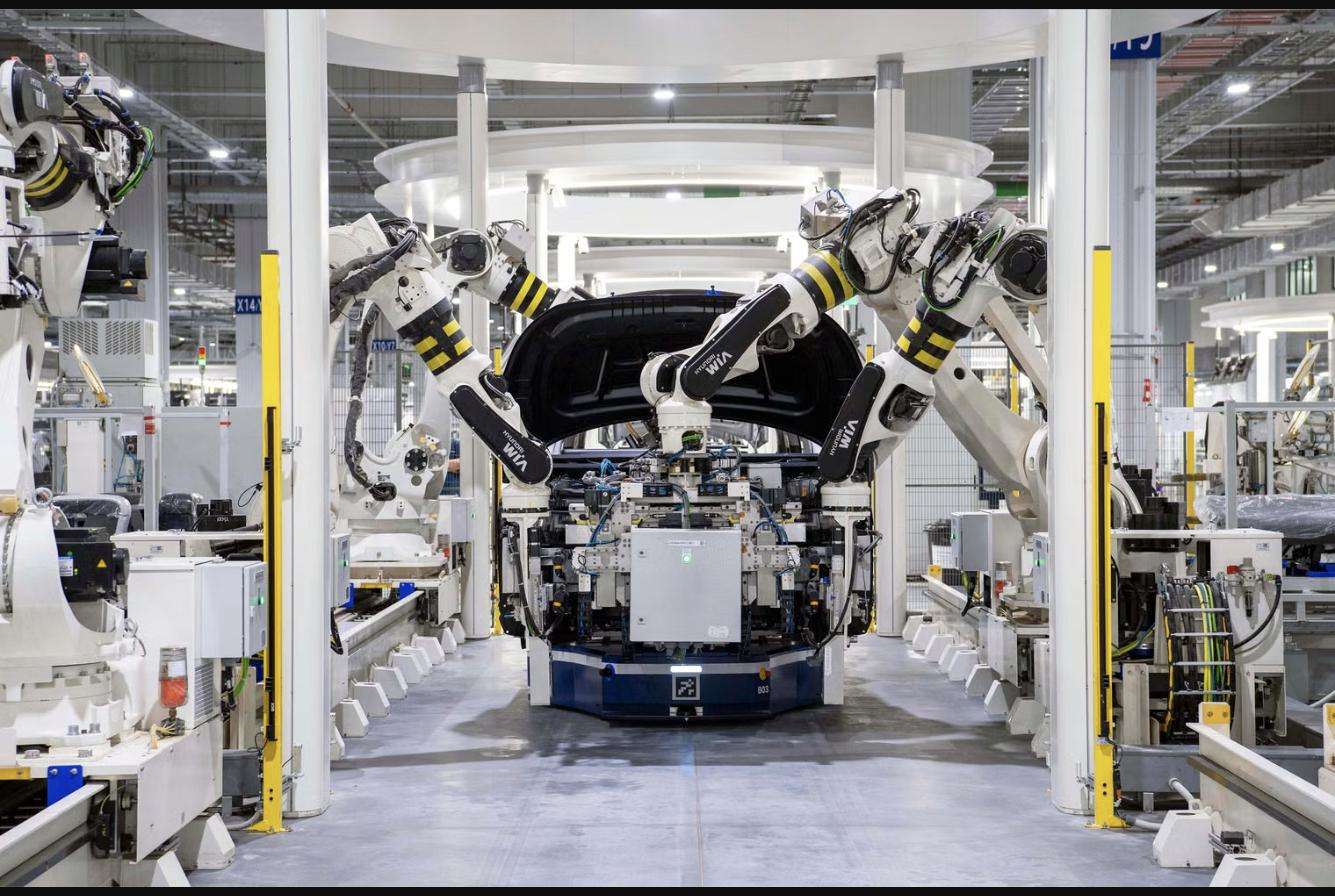 Robotic arms lifting a car body on an automotive assembly line