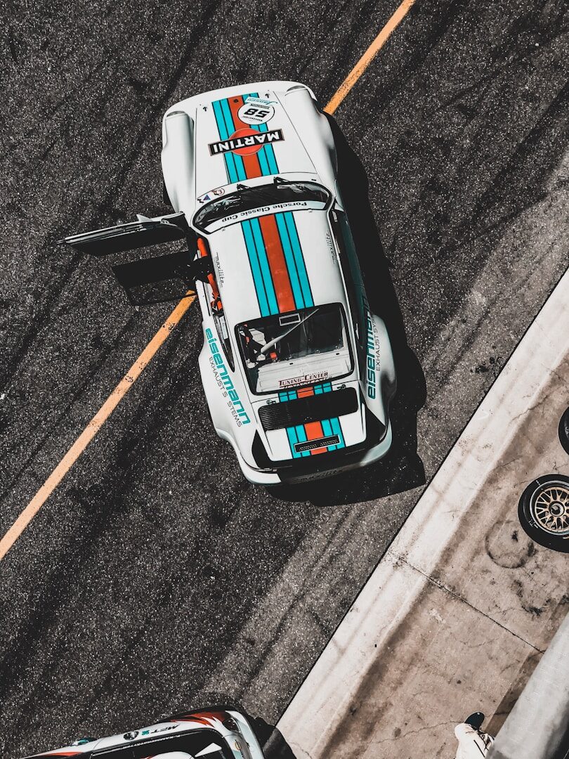 A white race car with blue and orange stripes on an asphalt track