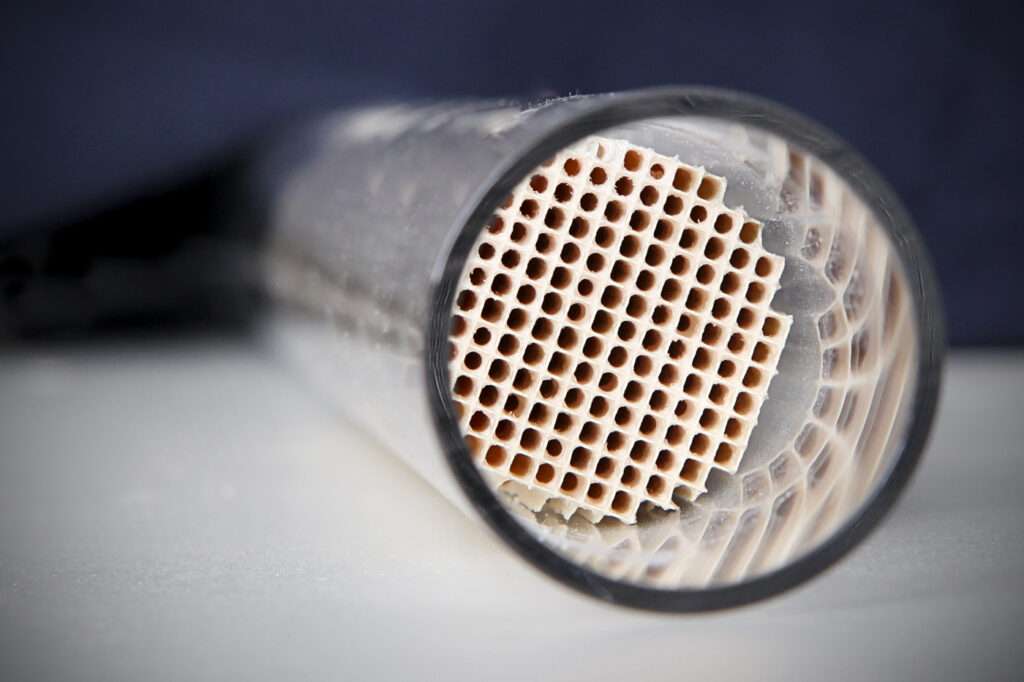 Cutaway of a ceramic honeycomb exhaust catalyst substrate inside a metal tube
