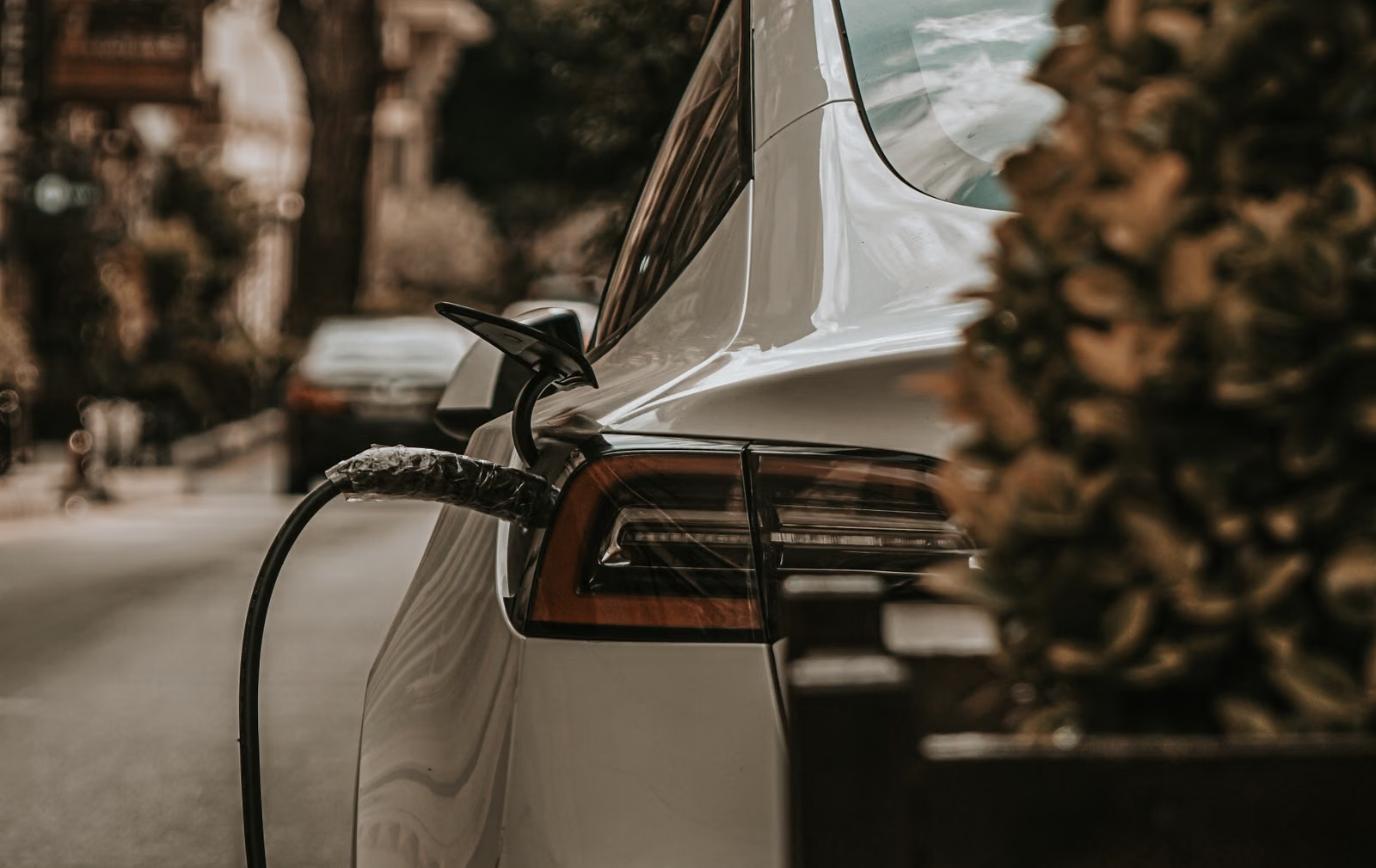 Electric vehicle plugged into a charging cable on a city street