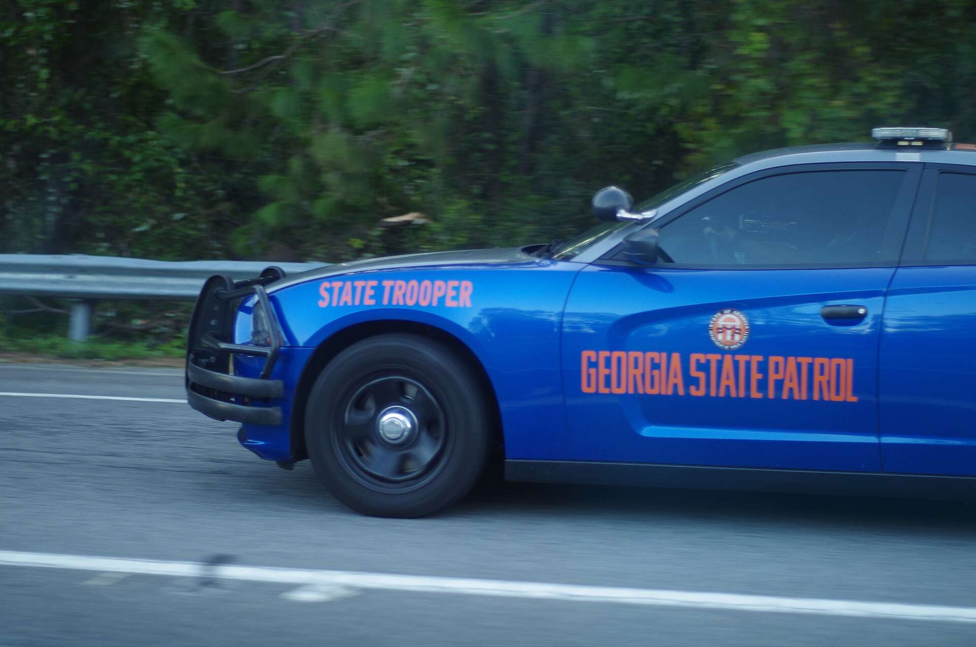 Blue Georgia State Patrol Dodge Charger with a push bumper moving along a highway