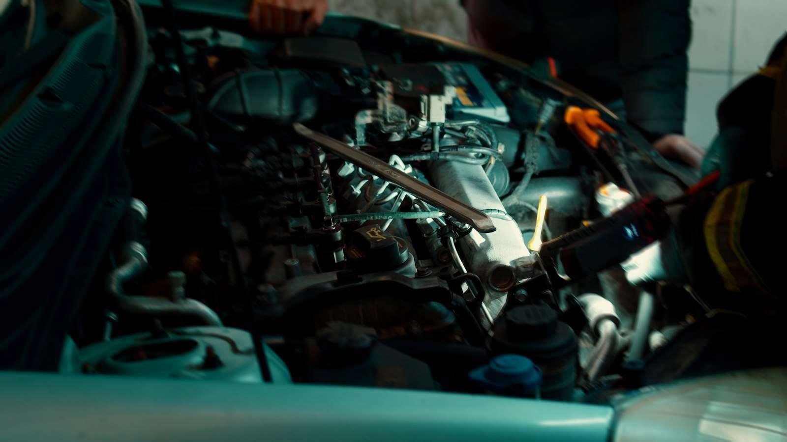 A mechanic works in an open engine bay, where a Ford wet timing belt runs inside the oil
