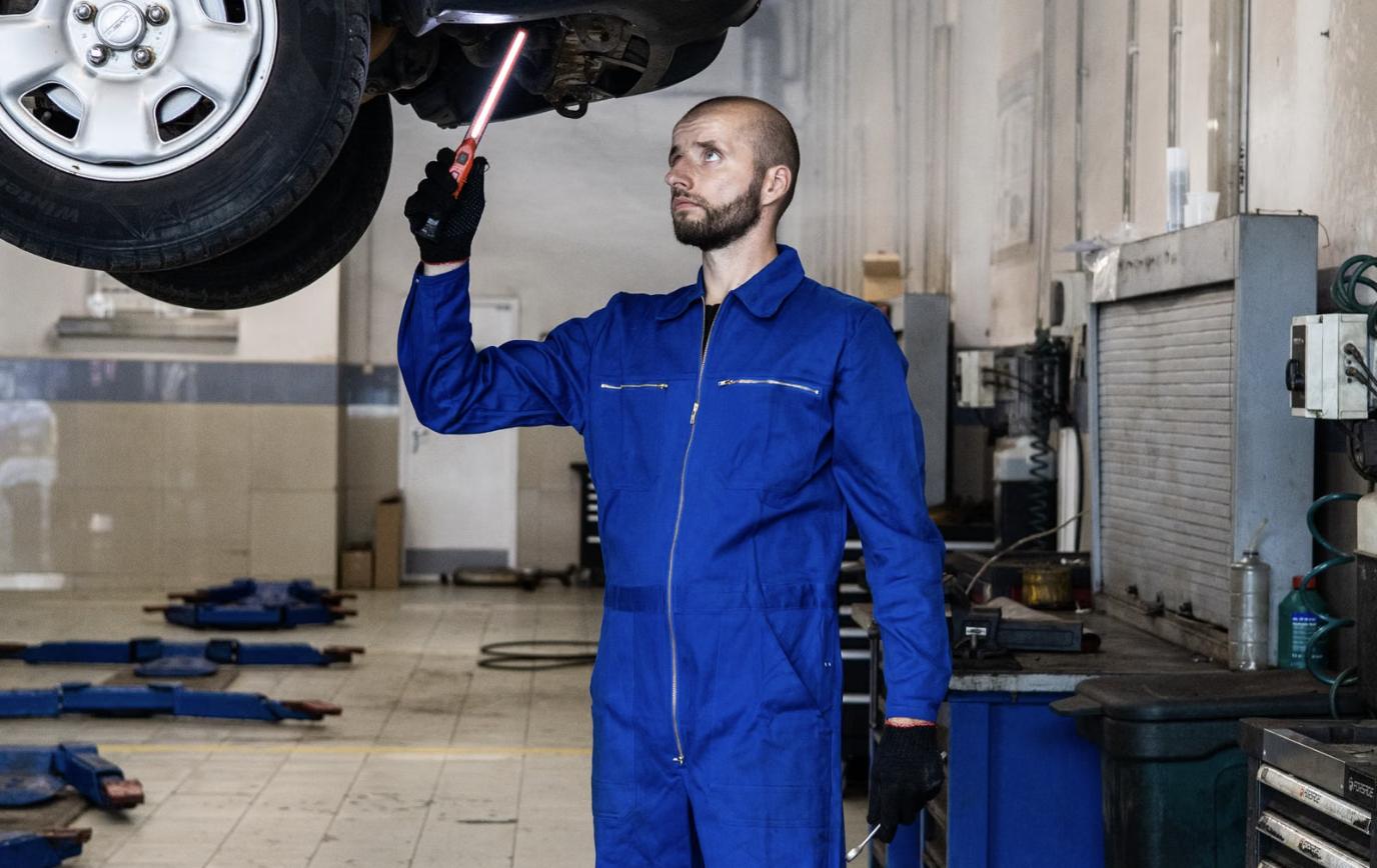 Technician servicing a vehicle on a lift in a dealership service bay