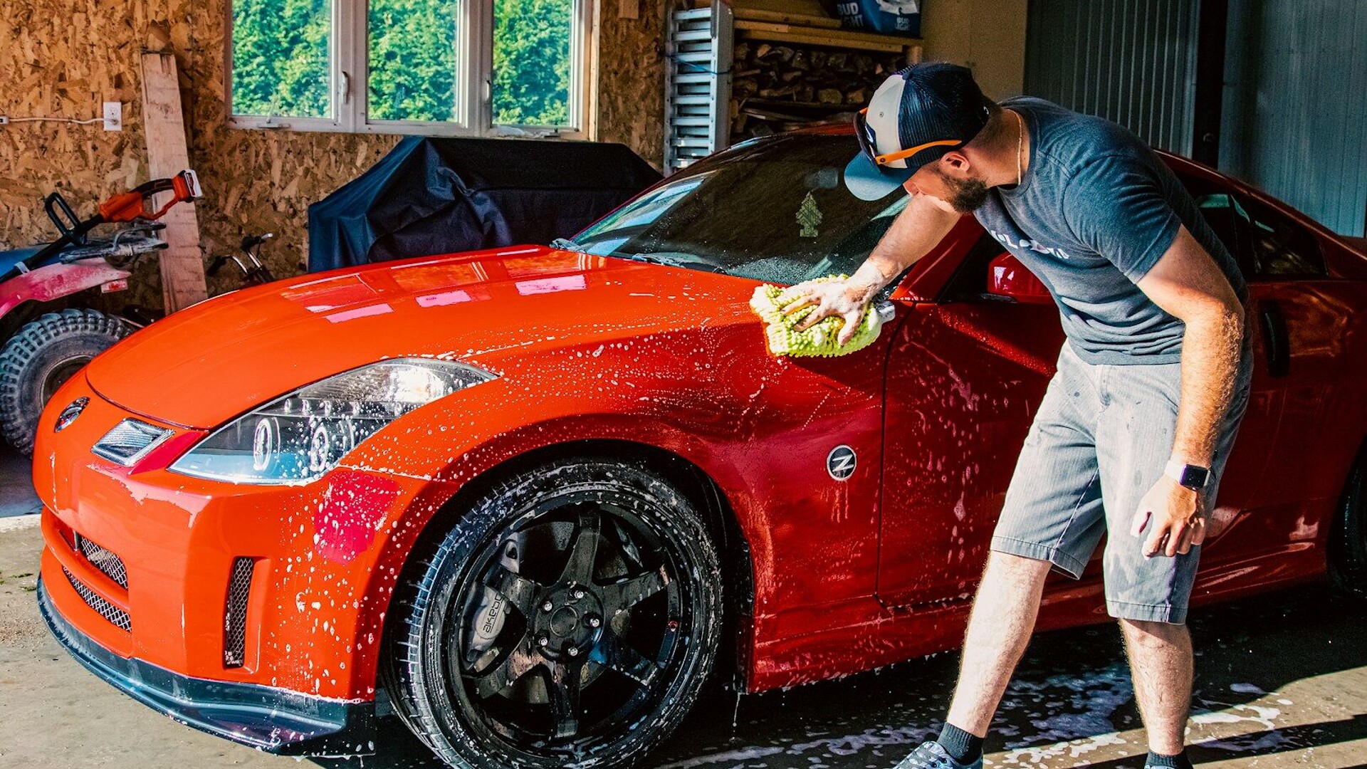 a man washing a red sports car in a garage