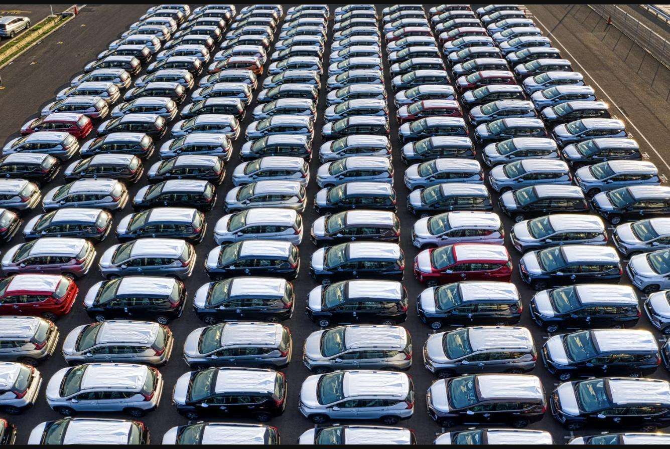 Rows of new cars parked in a shipping lot waiting to be loaded for export