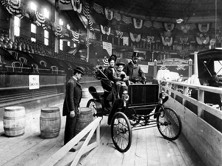 Black and white photo of a horseless carriage on display at the 1900 New York Auto Show
