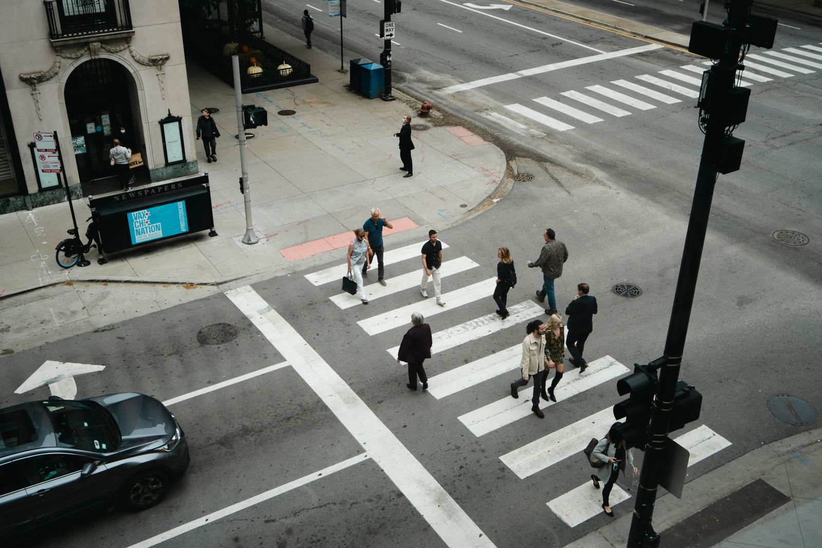 Aerial view of pedestrians crossing a city street at a marked crosswalk today