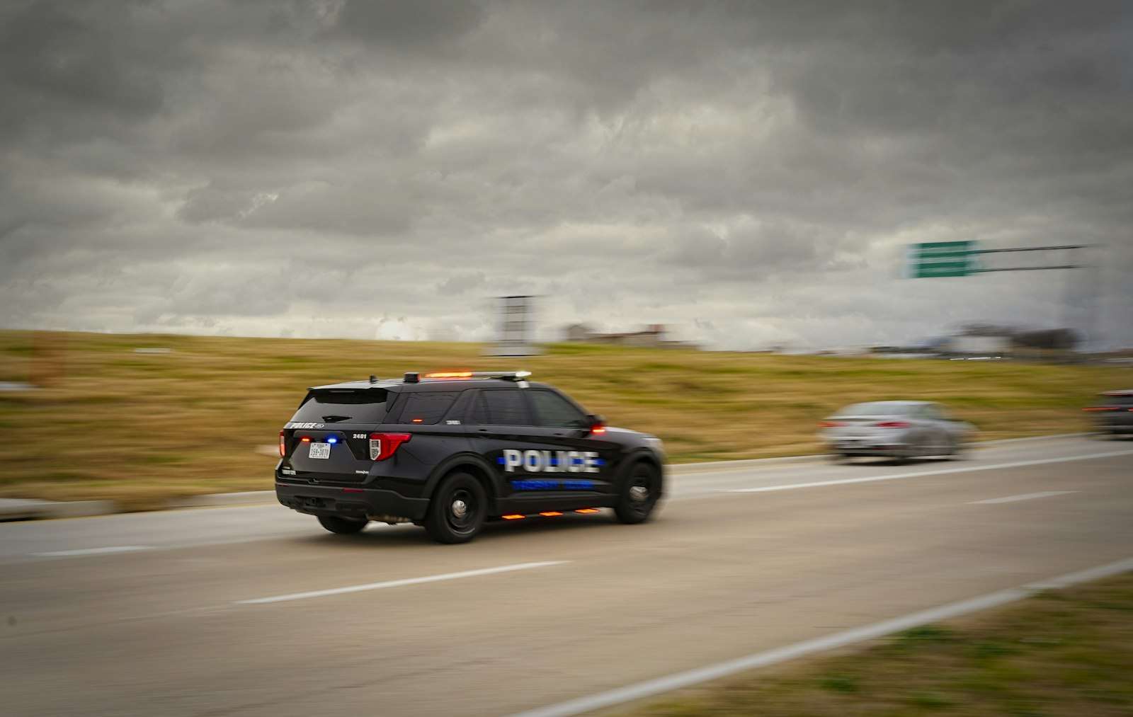 A police SUV running at speed on an interstate highway under a cloudy sky