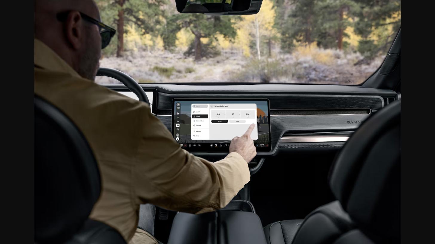 A driver scheduling a software update on a Rivian R1's center touchscreen
