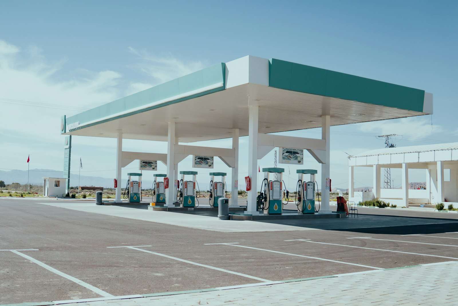 Row of gas pumps under a station canopy on a clear day