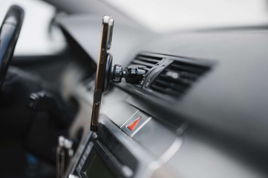 A smartphone held in a mount on a car dashboard near the air vents