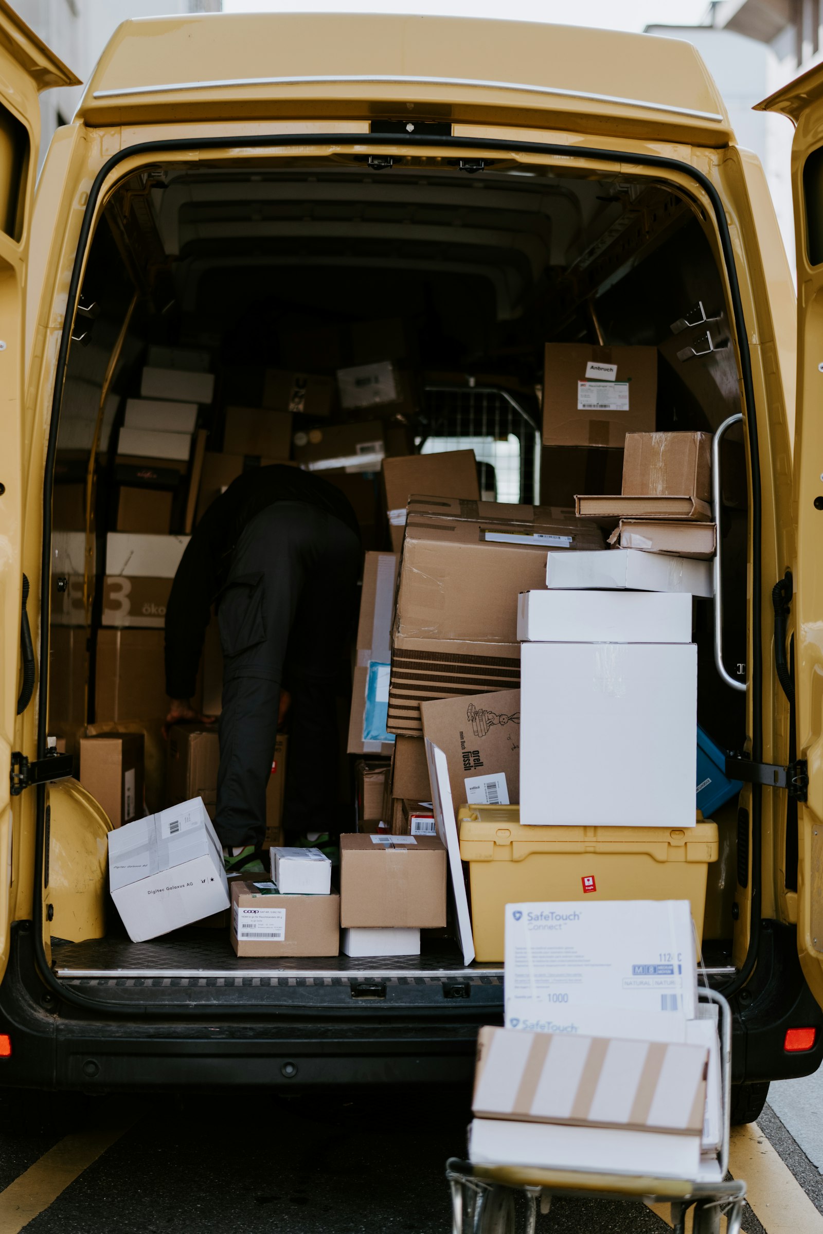 A person loading boxes into a yellow delivery van