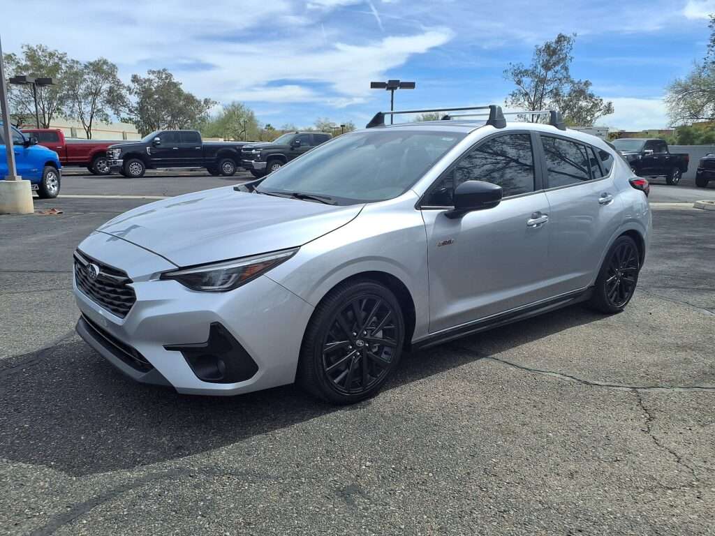 Silver Subaru Impreza RS with black wheels and roof rack at a dealership