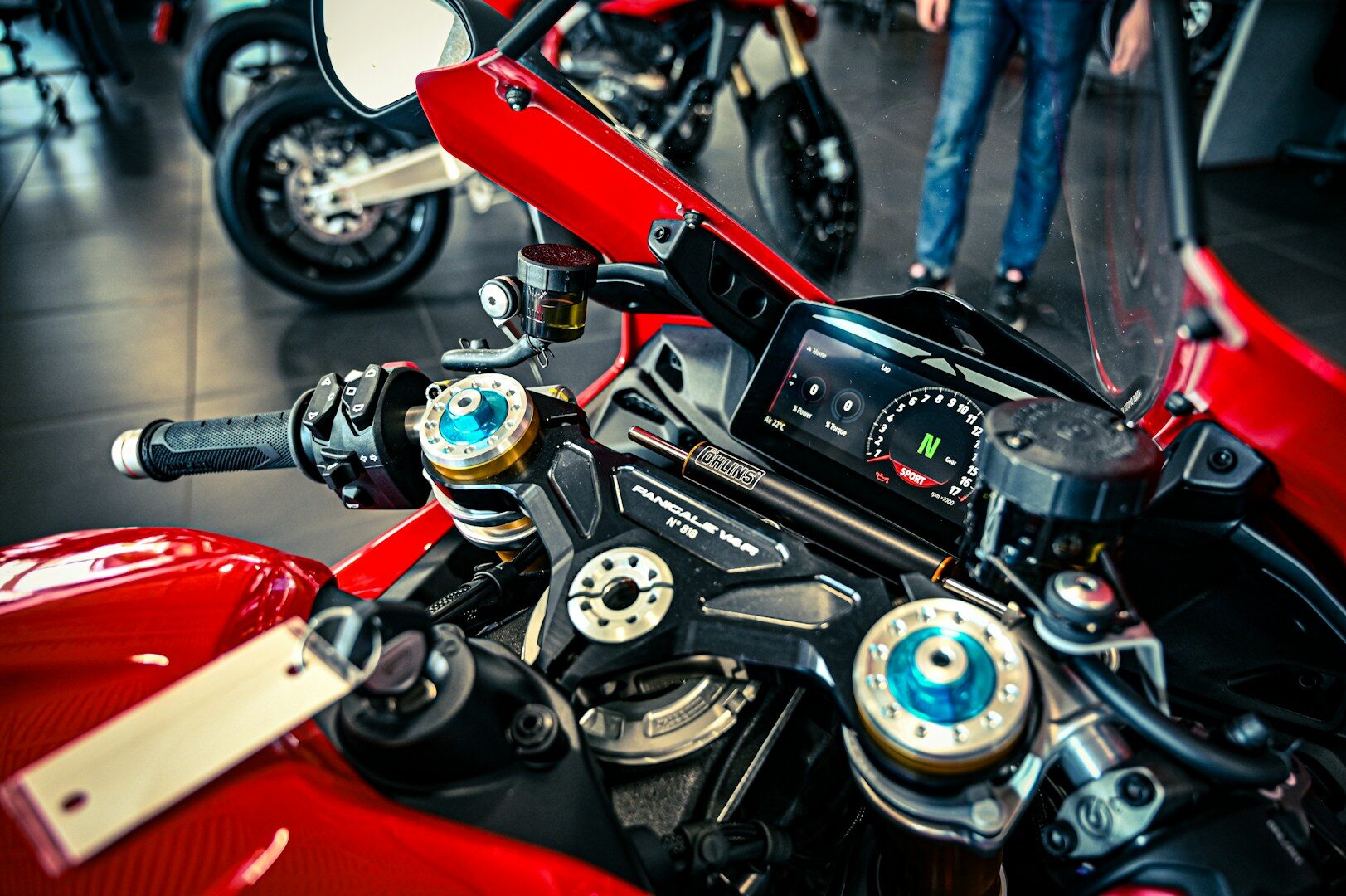 A red motorcycle's handlebars and digital dashboard are prominently displayed