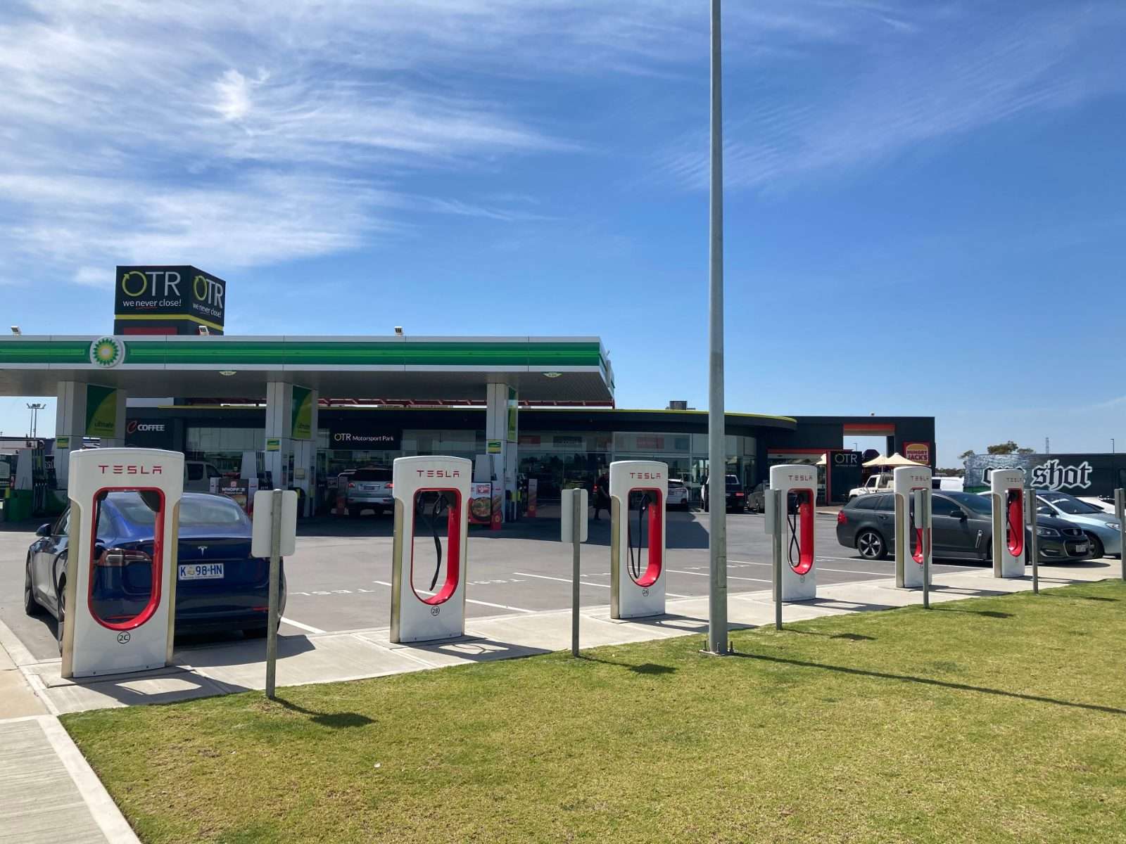 Row of Tesla Supercharger stalls, each with a single charging cable, in regional Australia