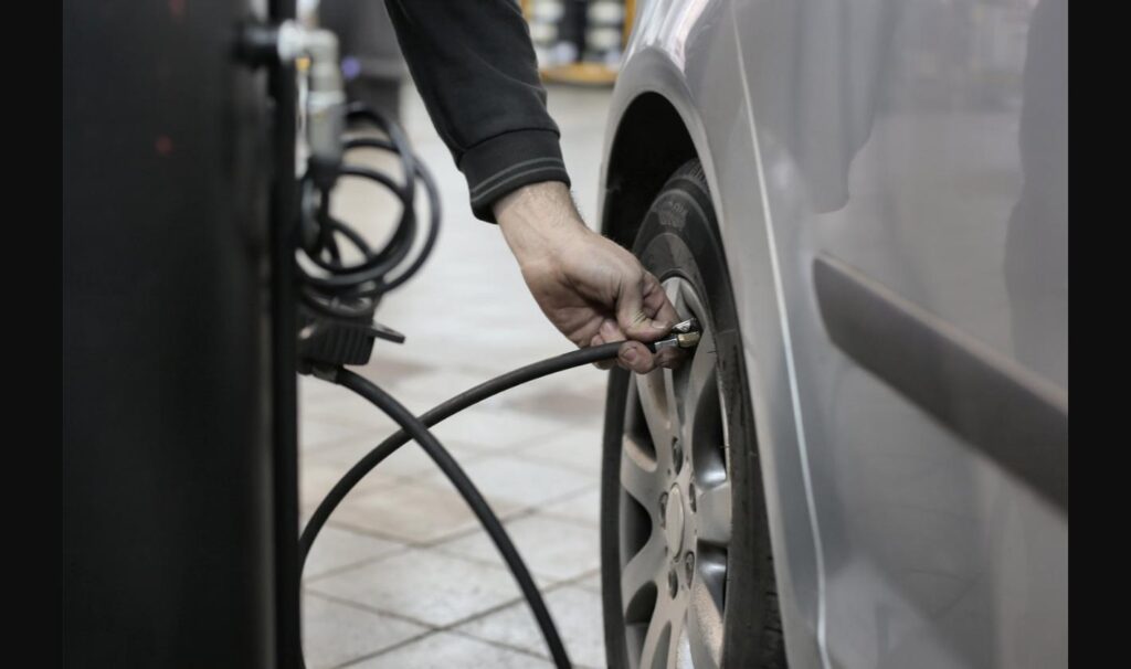 Mechanic checking tire pressure with a hand gauge, a good habit until the TPMS recall fix is installed