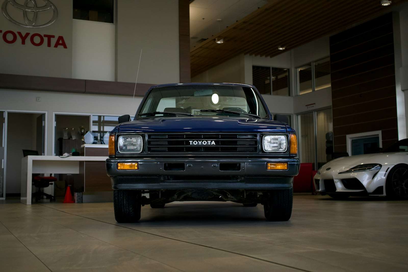 Blue Toyota pickup truck on display inside a car dealership showroom