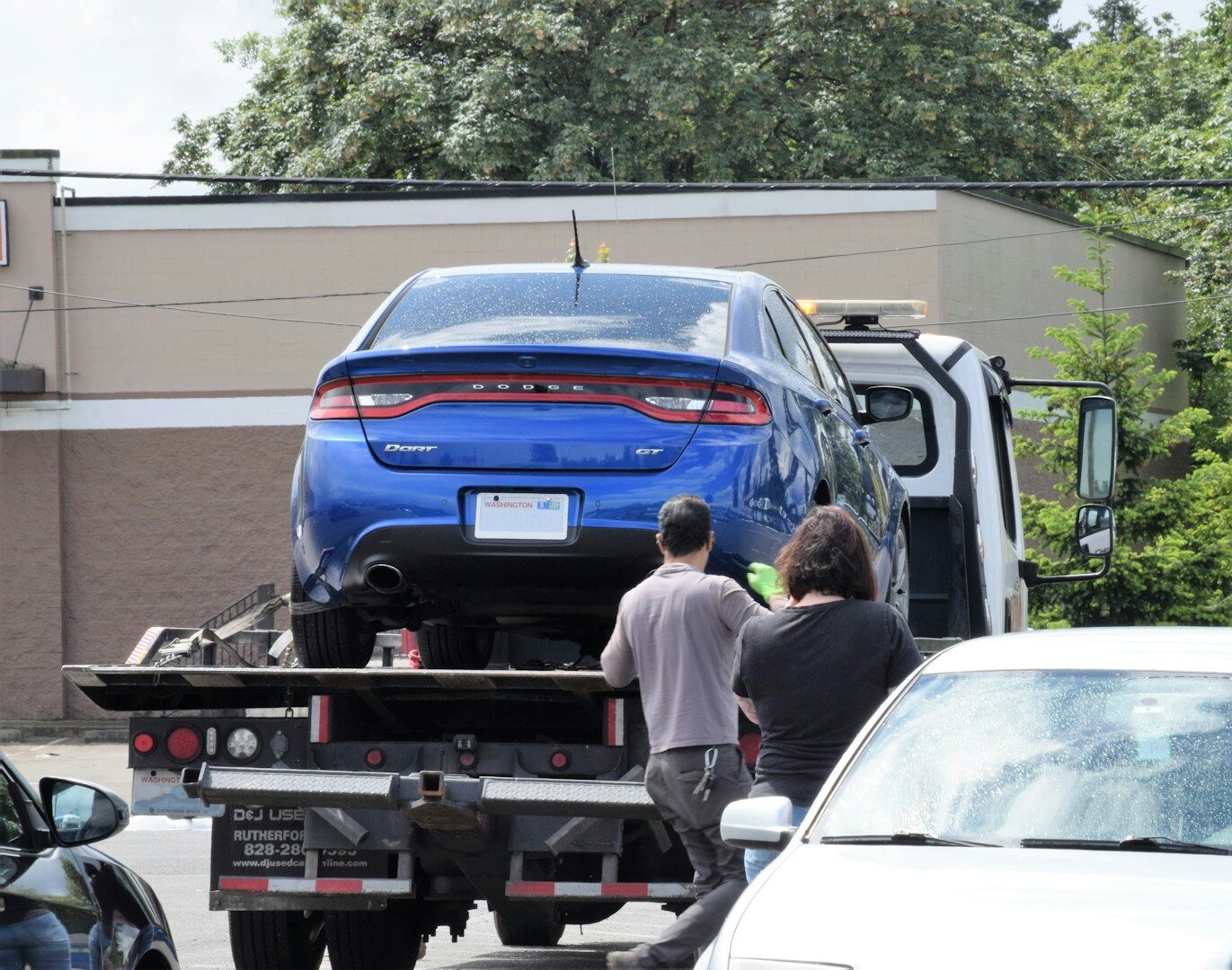Car being winched onto a flatbed tow truck, illustrating a paid-off car seized over an unrelated debt