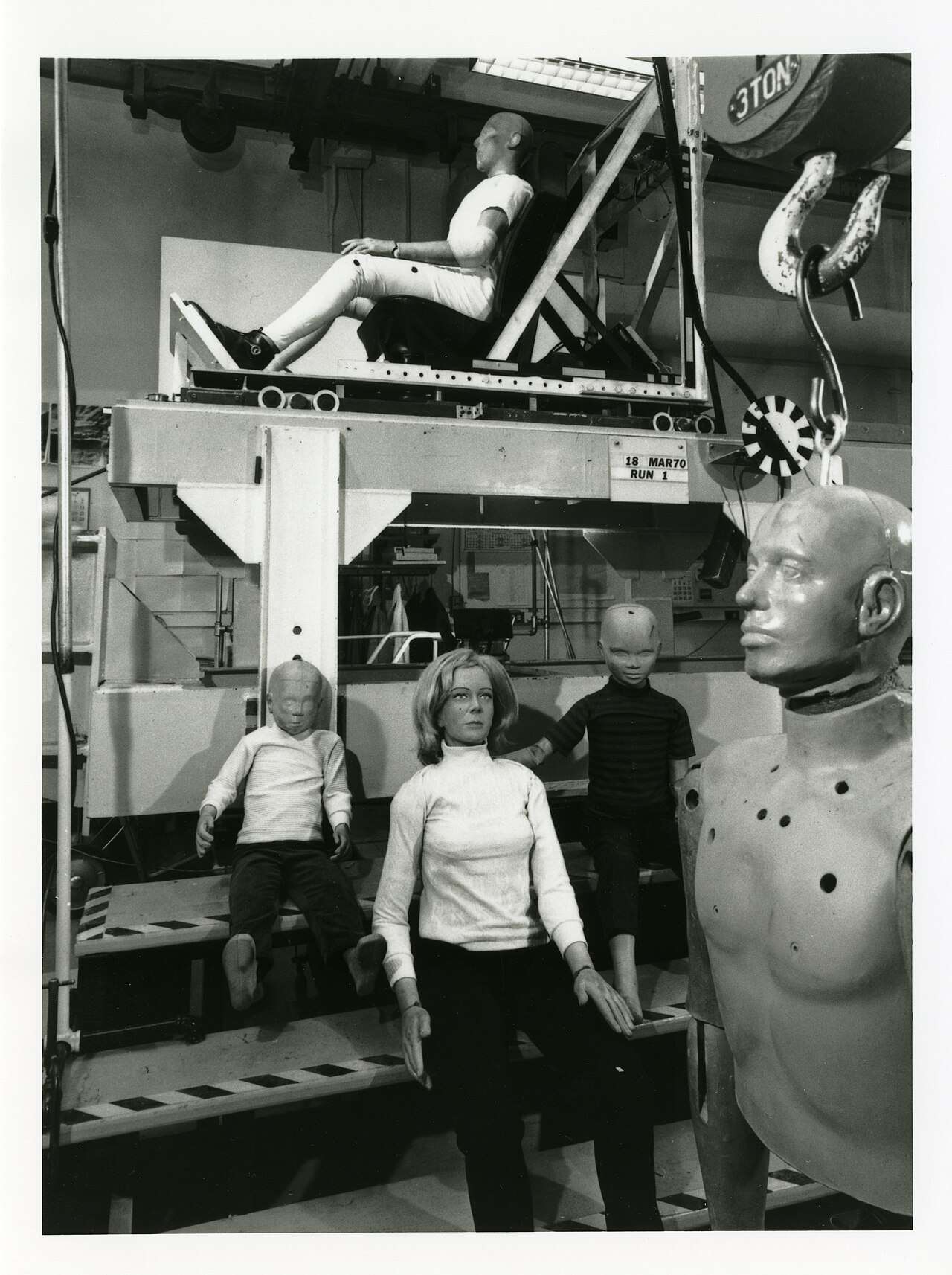 Archival photo of early crash test dummies of different sizes in a testing lab