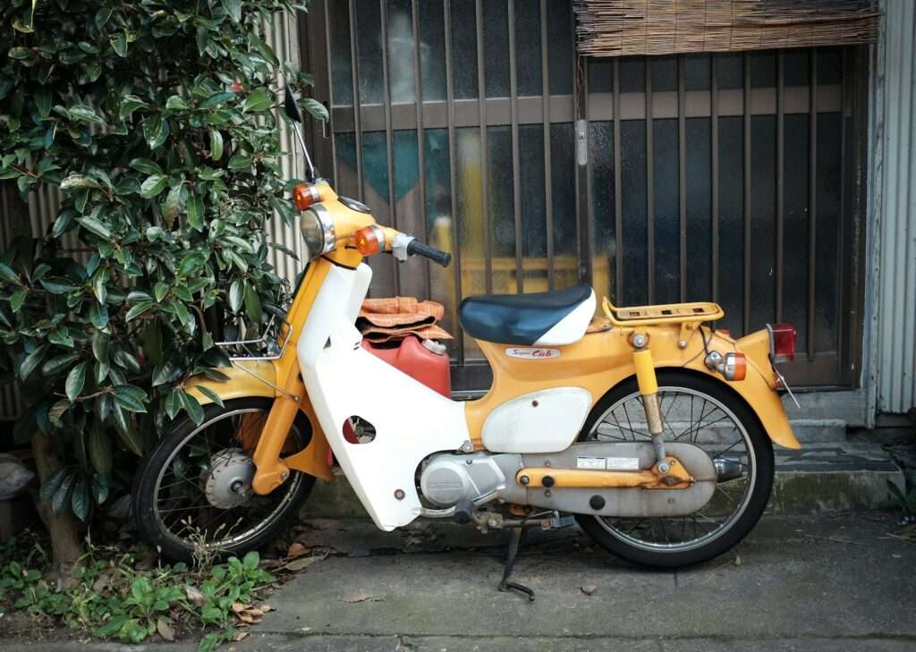 A vintage yellow and white Honda Super Cub parked on a street