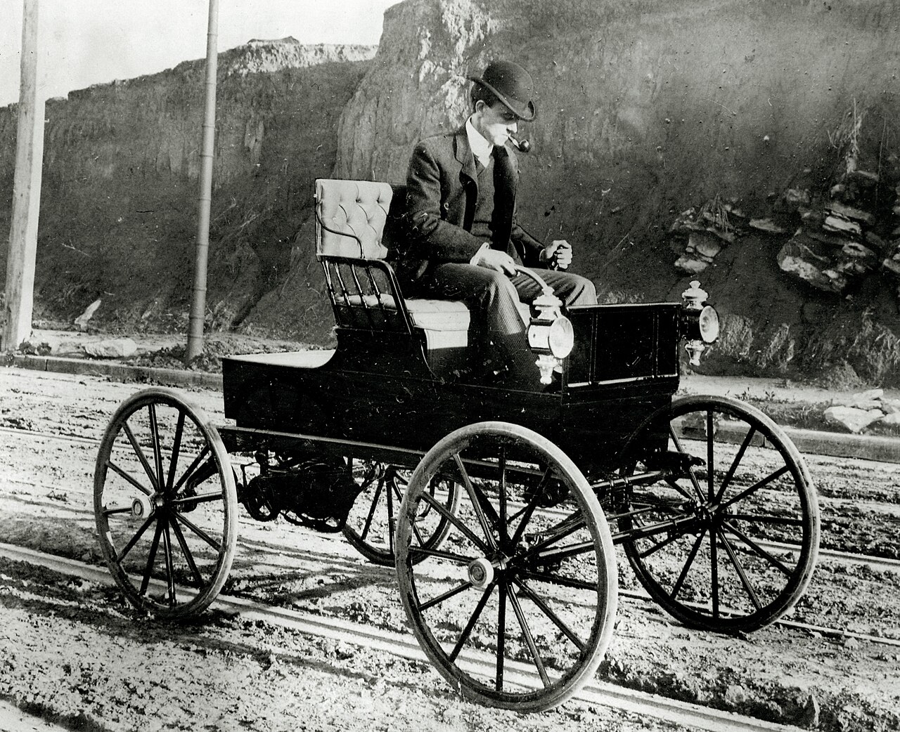 A man driving an early Woods electric buggy, an electric horseless carriage from 1900
