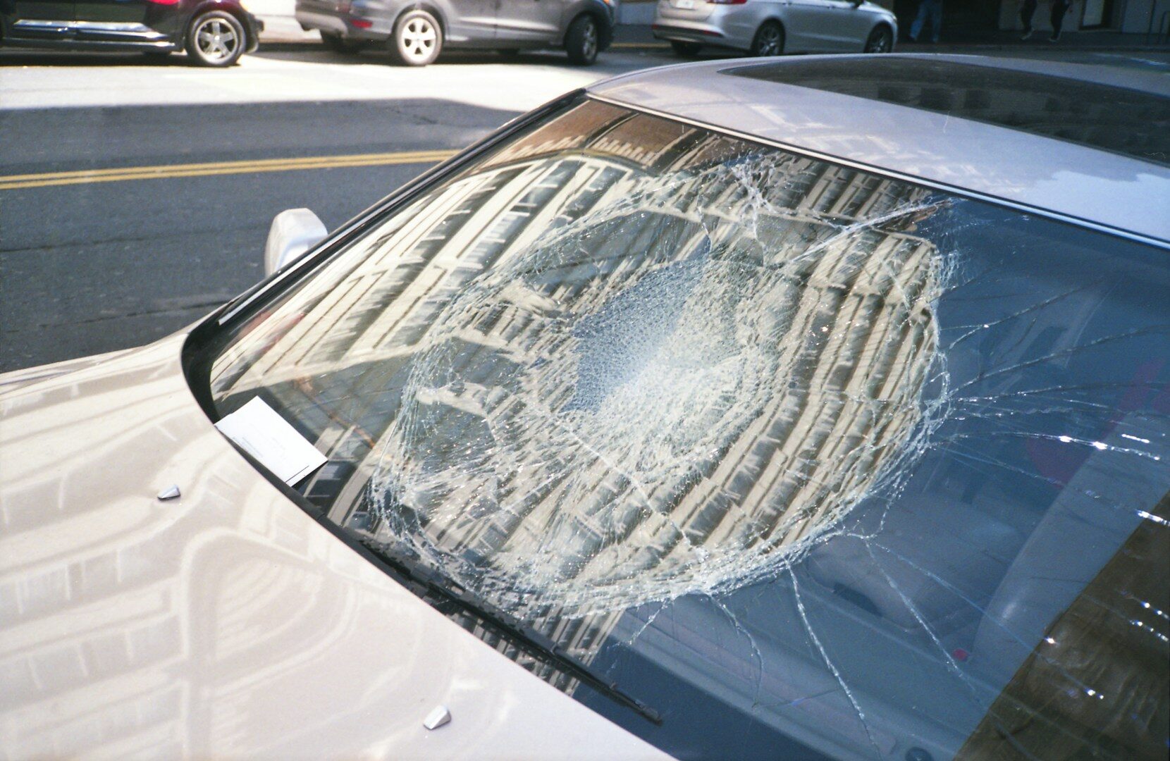 Shattered car windshield with spiderweb crack pattern