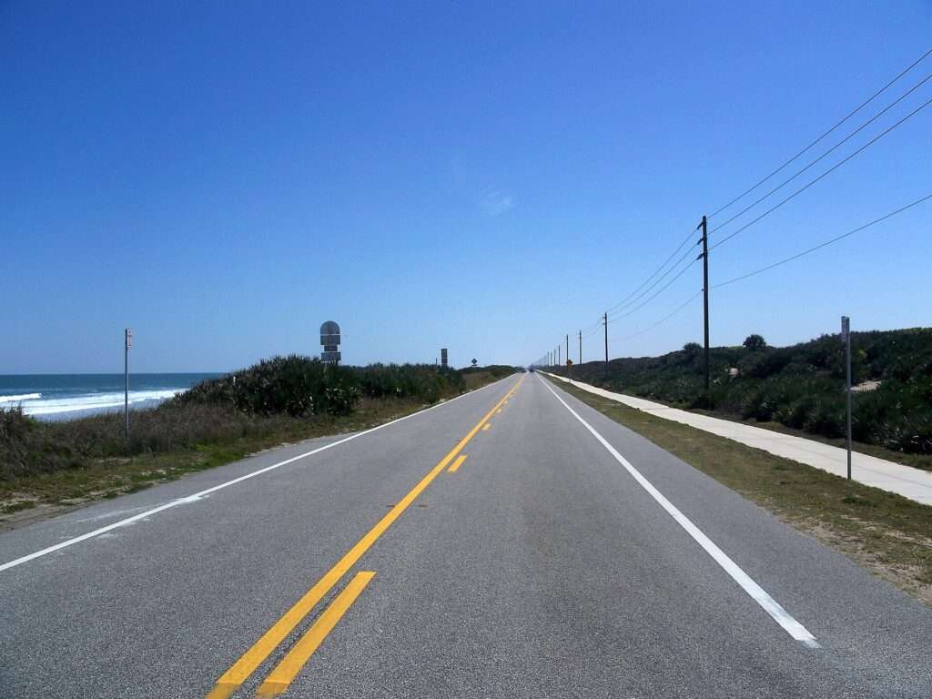 Two-lane State Road A1A with a double yellow center line running along the Atlantic dunes in Volusia County, Florida