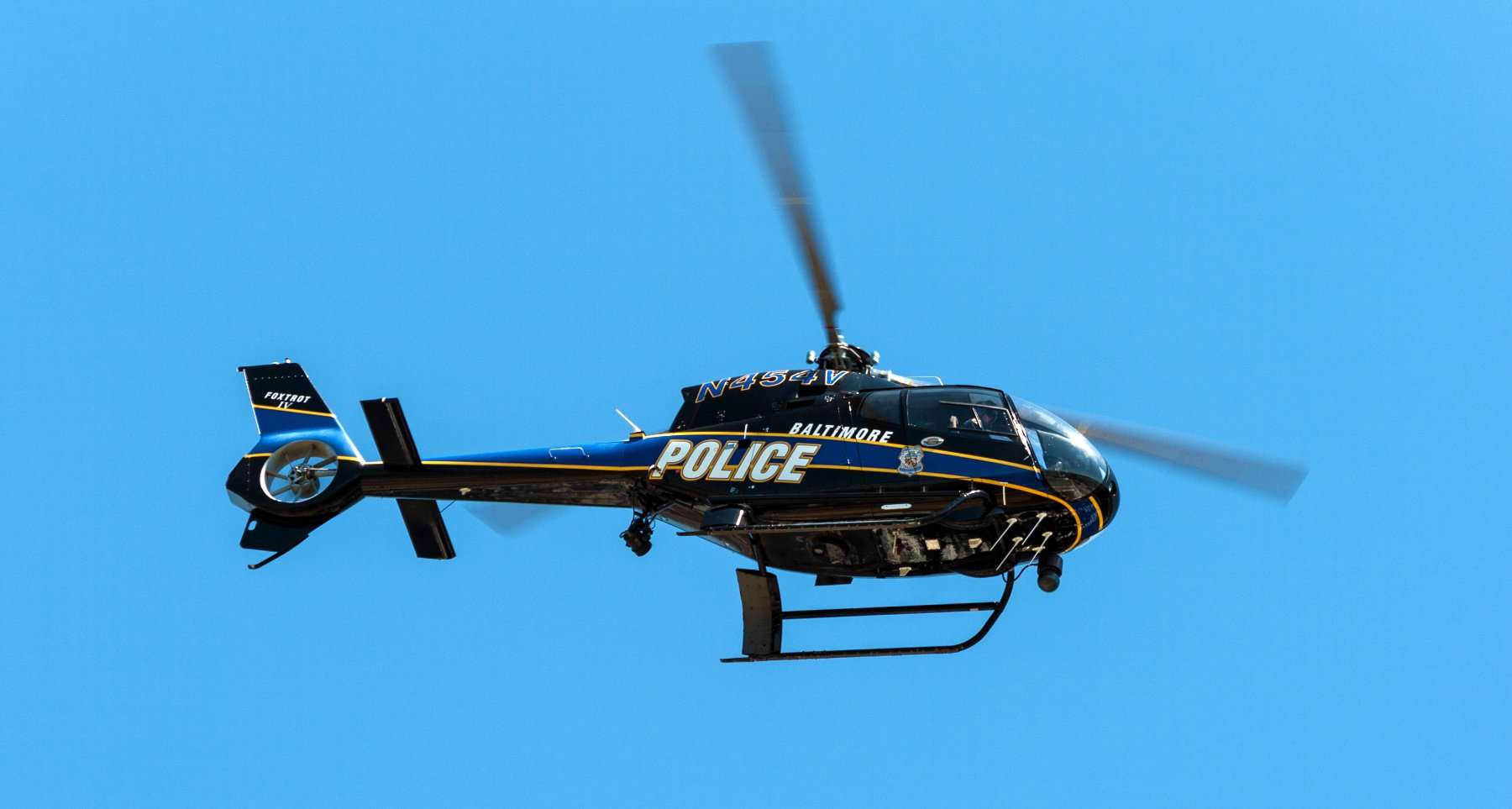 Baltimore Police Department Foxtrot helicopter in flight against a blue sky