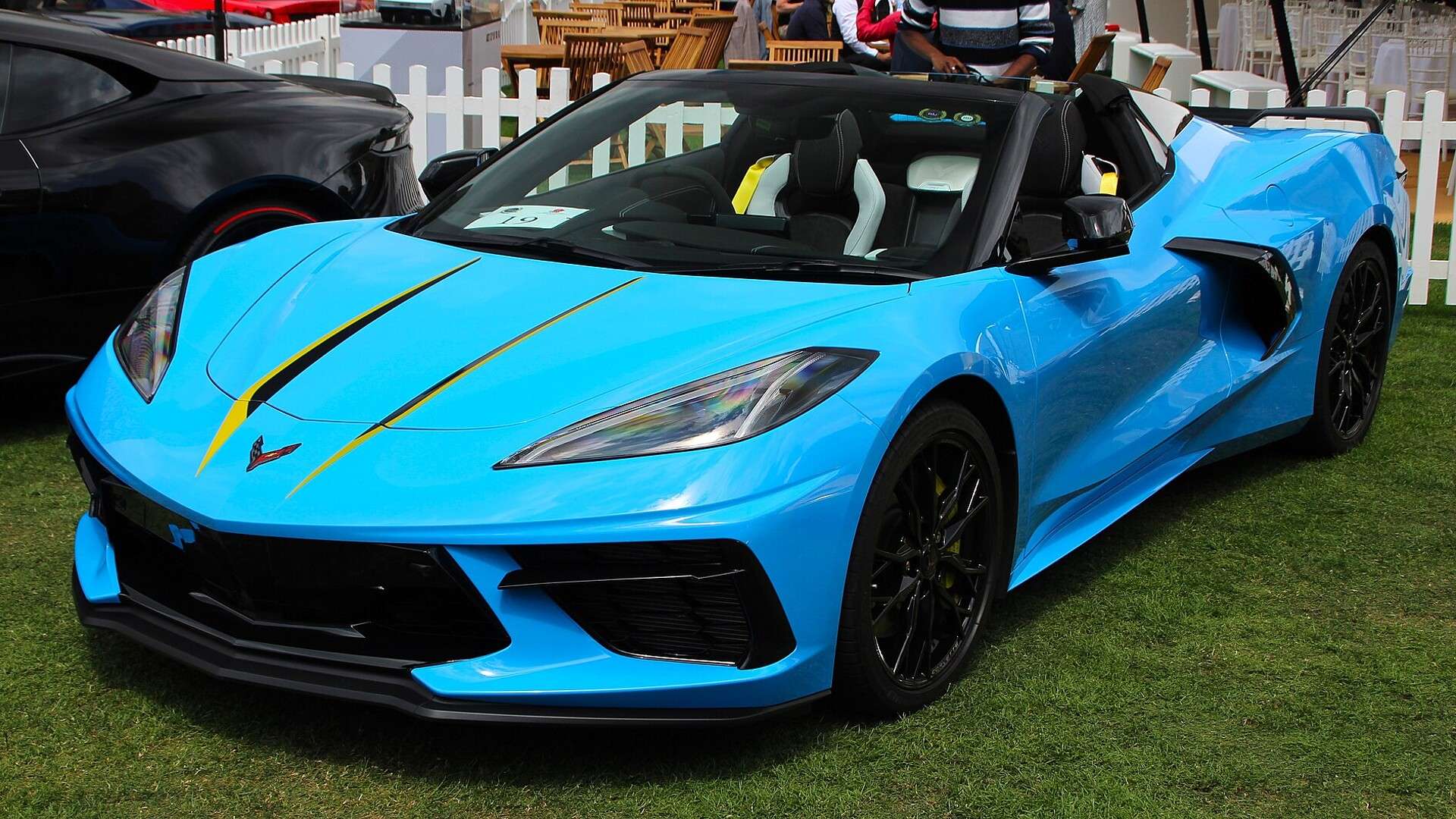 Light blue C8-generation Chevrolet Corvette Stingray convertible parked on grass at a car show