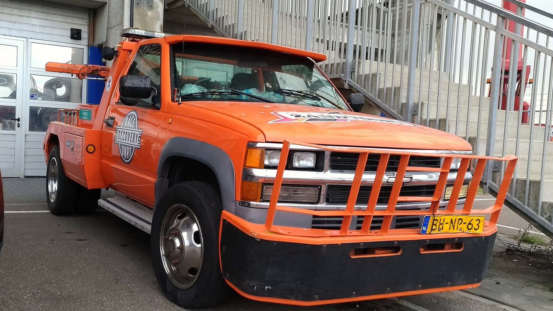 A Chevrolet 3500 HD dually tow truck parked at the curb