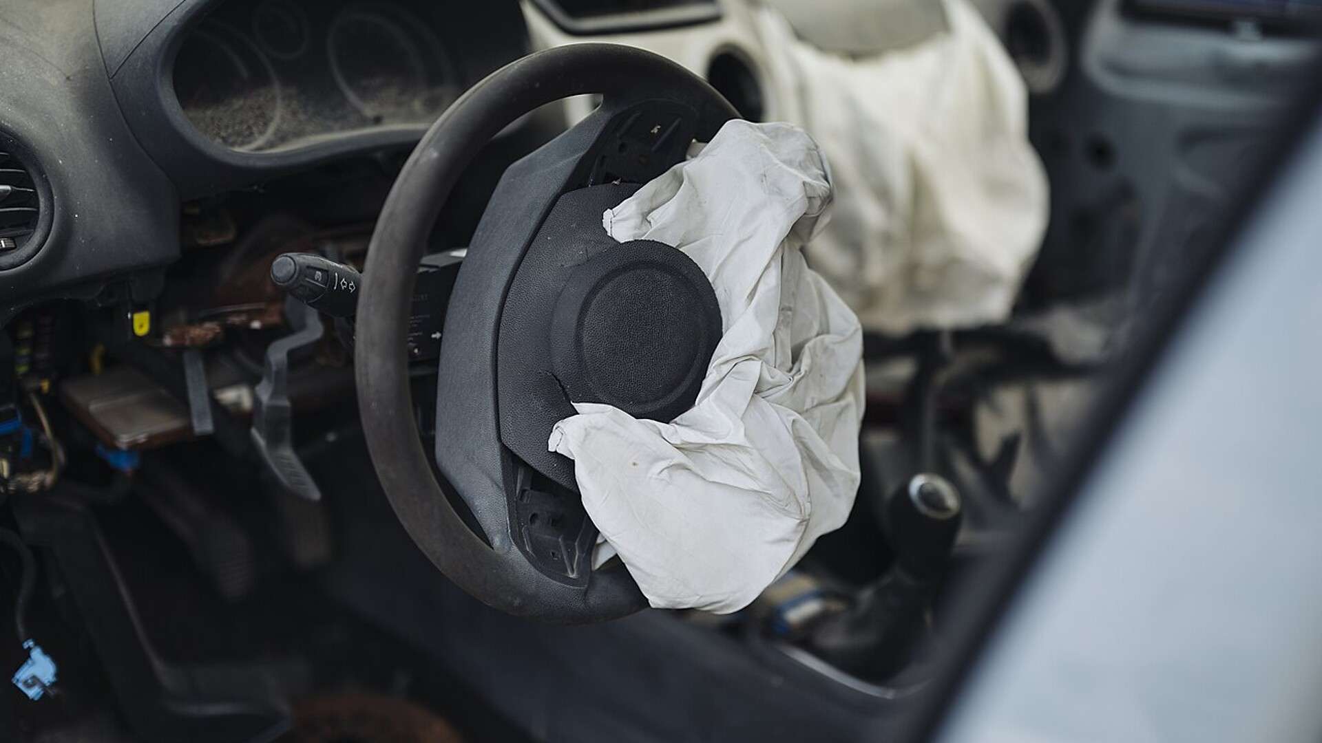 A deployed driver airbag hanging from a steering wheel