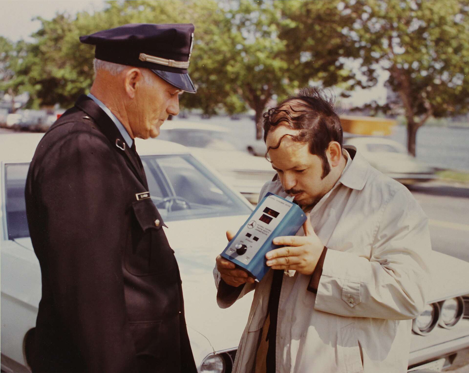 1972 photo of a U.S. DOT Transportation Systems Center staff member demonstrating a portable alcohol breath analyzer